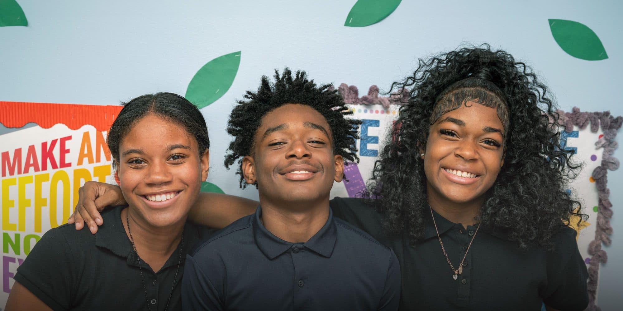 Three smiling Ohio College Preparatory students with their arms around each other.